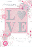 This softly romantic anniversary card combines gentle colours and thoughtful detail, creating a visual impression as tender as a hand-delivered bouquet arriving at a Brent doorstep. At its centre, the word LOVE is set in large, confident capitals, each one raised slightly from the card's surface and dusted with fine, glistening glitter. The shimmer is subtle, catching the light like tiny reflections on the Brent Reservoir, and gives the letters an inviting, tactile quality. These letters rest upon a blush-pink panel, framed by delicate shading that helps the central word stand out, almost as if it were floating. Around this key motif, an arrangement of stylized flowers and curling vines cascades across the card. The blossoms, drawn with slender, graceful lines, open in shades of blush, pale pink, and soft ivory, accented with hints of silvery grey to suggest foiled highlights. Slender stems and leaves loop and arc between the flowers, mirroring the natural movement of stems in a florist's hand-tied anniversary bouquet. The background remains a quiet, pastel pink wash, lending the whole design a dreamy, slightly hazy atmosphere, like looking back at shared moments through the lens of memory. Among the flowers, small hearts and intricate decorative swirls add touches of intimacy and whimsy, reinforcing the theme of enduring romance. A beautifully scripted anniversary message nestles beside the floral motif, its curves and loops echoing the design's flowing lines and expressing a promise of ongoing love. Seen together, the raised glitter letters, the blush and silver palette, and the delicate florals form a card perfectly suited to accompany anniversary flowers sent across Brent, from family homes in Kingsbury to apartments near Park Royal.